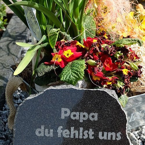 Grab mit Blumen und Gedenkstein mit der Inschrift Papa du fehlst uns geschmückt
