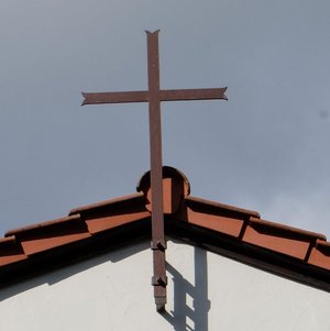 Friedhofskapelle mit Kreuz am Dach und der Aufschrift RIP