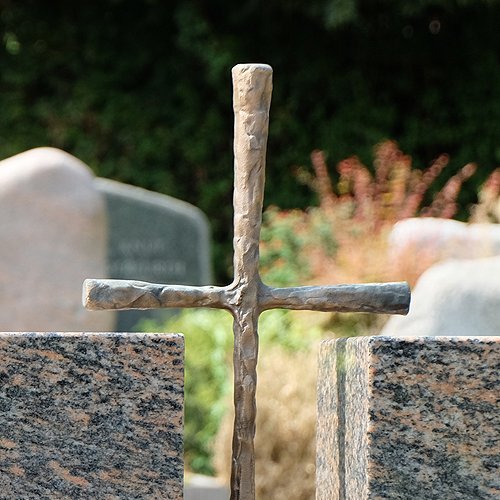 Grabmal aus Stein mit Kreuz aus Metall