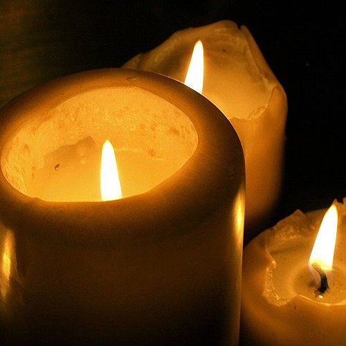 Drei brennende Kerzen in der Dunkelheit